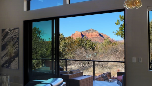 A modern interior with large windows, a wooden deck, and a mountain view. -  Stunning 3 bed, 2 bath home w/Bell Rock and Castle Rock views (Sedona)