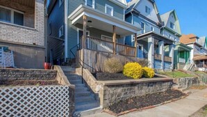 A row of townhouses with a front porch, a stone retaining wall, and a small garden area.