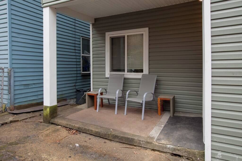 A porch with three chairs and a window.