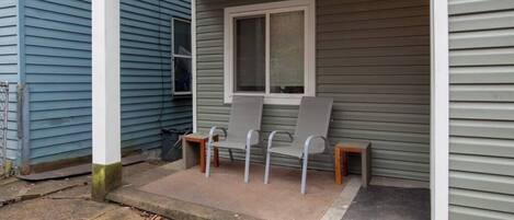 A porch with three chairs and a window.