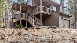 A two-story house with a balcony on the second floor, a staircase leading to the balcony, and a chimney on the roof. - ASHW05 - Charming Home, A/C, Hot Tub,  Bikes (Sunriver)