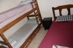 A bunk bed with a wooden frame, a single bed with a red bedspread, and a small black nightstand.