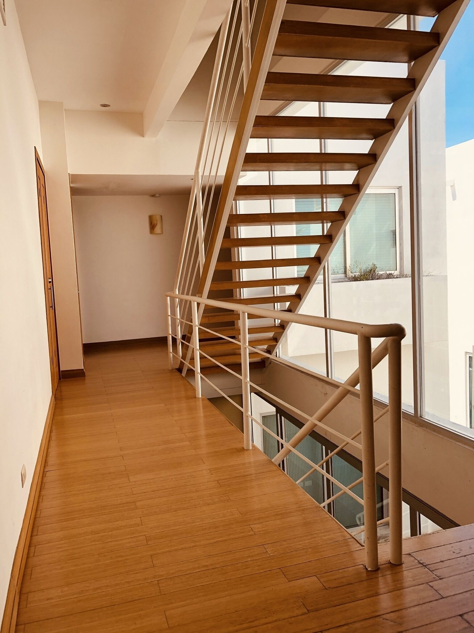 A modern interior with a wooden staircase and a view of the outside.