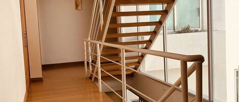 A modern interior with a wooden staircase and a view of the outside.