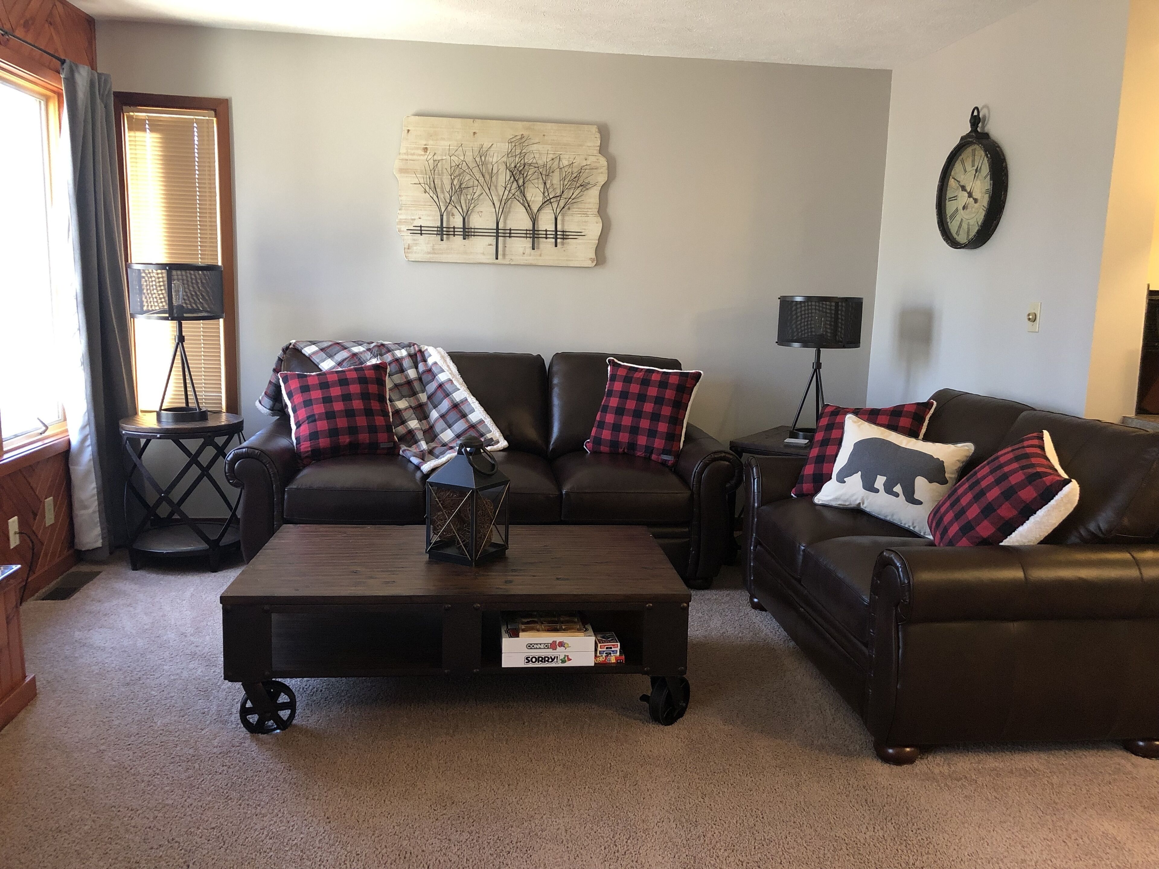 A living room with two leather sofas, a coffee table with a box, a wall clock, and a lamp.