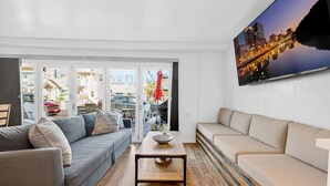Ein modernes Wohnzimmer mit einem grauen Sofa, einem beigen Sofa, einem Holztisch und einem Stadtbild an der Wand.