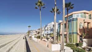 Ein Strandhotel mit einer Reihe von Palmen, einem Sandstrand und einem klaren, blauen Himmel.