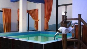 Área da piscina com vista para as montanhas, uma cadeira de madeira e cortinas laranja.