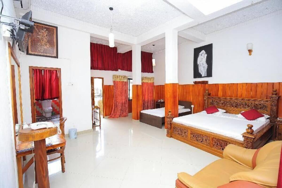 Quarto de hotel com uma cama grande, uma escrivaninha, uma cadeira e um guarda-roupa.