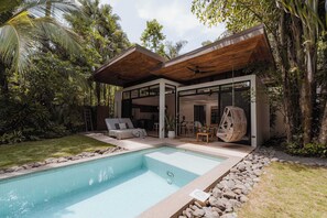Ein modernes Haus mit Swimmingpool, Holzterrasse und üppiger Bepflanzung.