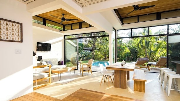 Un'ampia zona giorno con un grande tavolo di legno, numerosi posti a sedere e vista su una piscina.