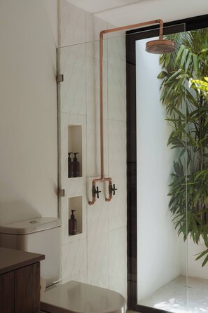 Ein modernes Badezimmer mit Duschkabine aus Glas, einer Bambuspflanze und integrierten Seifenspendern.