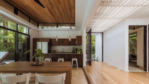 Una cucina moderna con mobili in legno, un tavolo da pranzo con sedie e un'ampia finestra vista su spazi verdi.