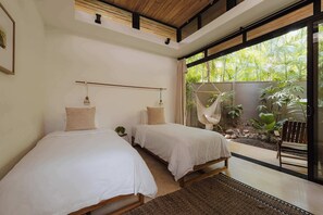 Ein Schlafzimmer mit zwei Betten, einer Hängematte und Blick auf einen Garten.