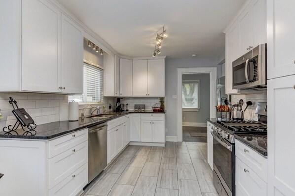 Fully equipped kitchen with stainless steel appliances, sink, and range hood.