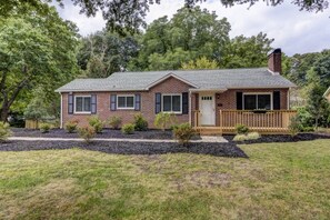 Situated on a well-manicured lawn, this charming house boasts a gabled roof and a welcoming front porch.