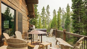 Een houten terras met Adirondack-stoelen, een vuurkorf en een barbecue.