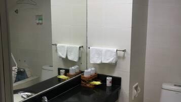 A bathroom with a black sink, white toilet, and a mirror. There are towels hanging on the wall and a shower curtain rod above the sink.