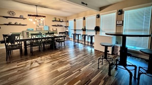 Una cocina amplia con ventilador de techo, piso de madera y un comedor con taburetes de bar.