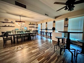 A spacious kitchen with a ceiling fan, wooden flooring, and a dining area with bar stools.