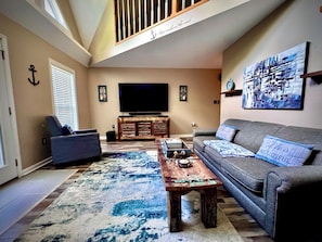 A living room with a sofa, a coffee table, a TV, and a large painting on the wall.