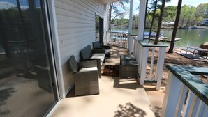 A covered outdoor deck with seating, a view of a lake, and docked boats. - Lakefront Walkout Condo in StillWaters – Stunning Views & Prime Location! (Dadeville)