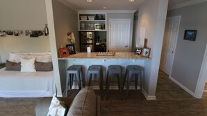 A compact kitchen with a central island, bar stools, and a refrigerator. - Lakefront Walkout Condo in StillWaters – Stunning Views & Prime Location! (Dadeville)
