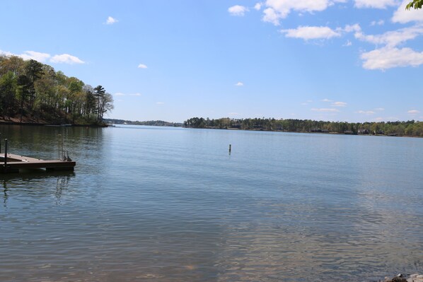 Um lago tranquilo com um cais e árvores ao fundo.