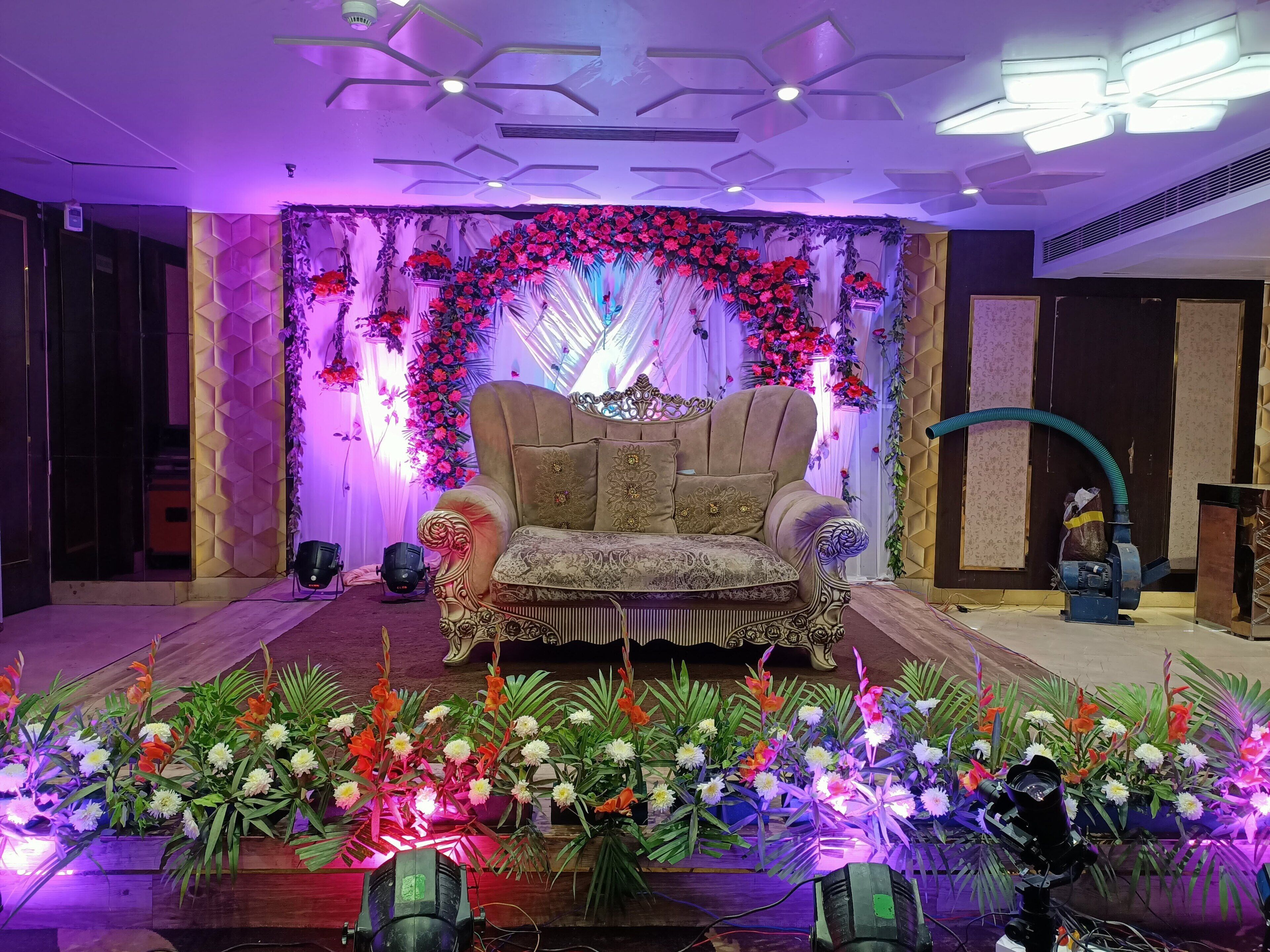 A stage with a sofa and floral decorations, surrounded by potted plants.