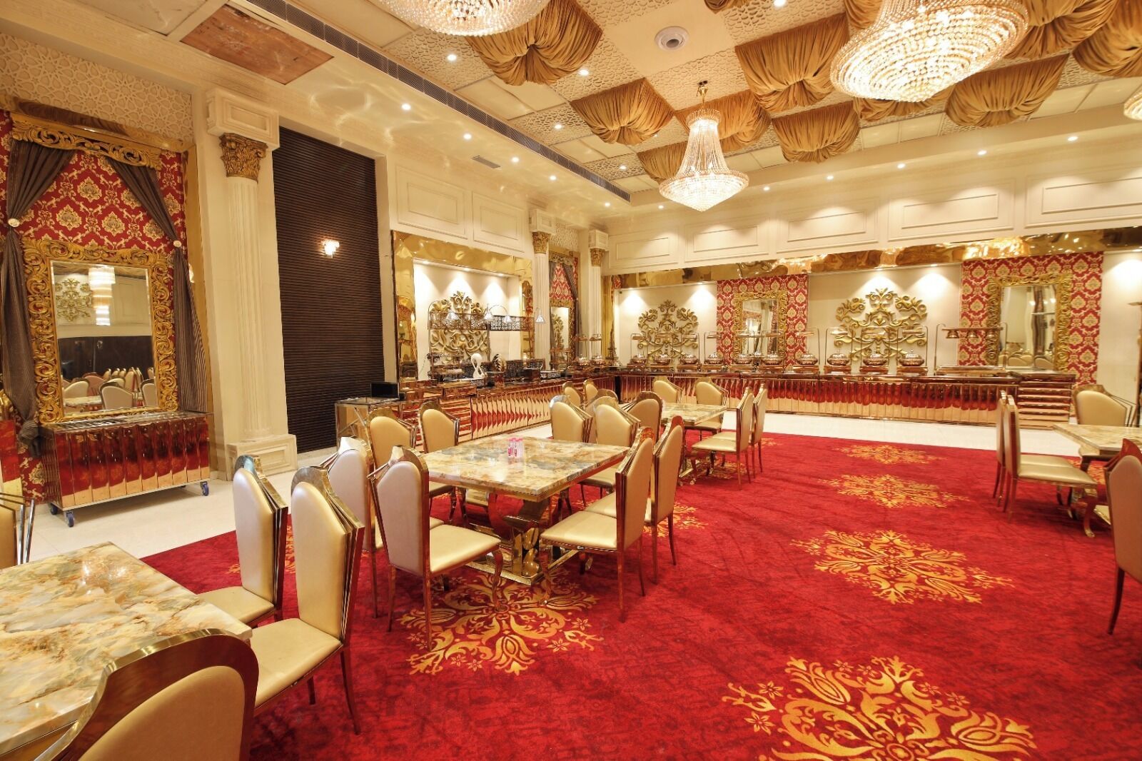 Une salle de banquet luxueuse, ornée de lustres somptueux, dotée d’un sol recouvert d’une moquette rouge et d’une longue table à manger entourée de chaises.