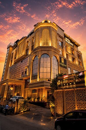 A hotel with a large arched entrance, multiple windows, and a prominent sign. - Hotel Harmony Inn (Meerut)