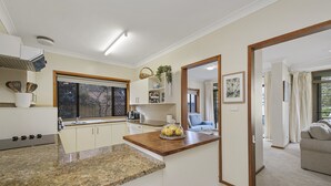 Eine moderne Küche mit Granitarbeitsplatten, einem eingebauten Backofen und einem Fenster mit Blick auf einen Garten.