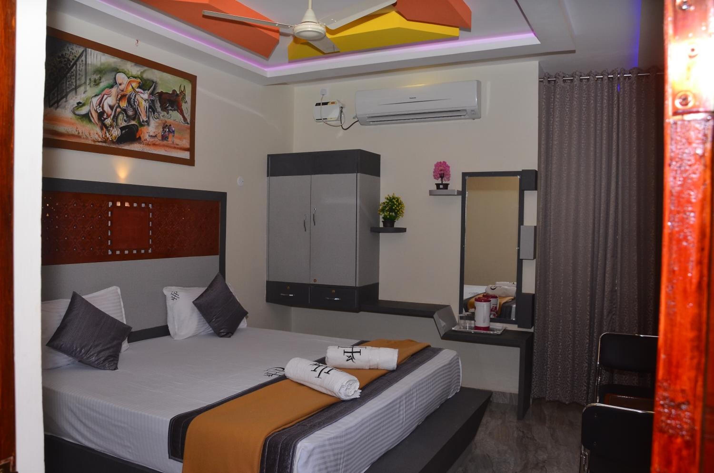 Une chambre d’hôtel comprenant un lit, une armoire, un bureau avec une chaise, un miroir et un appareil de climatisation.