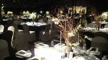 A formal dining area with tables set for multiple guests, each with place settings and floral centerpieces.