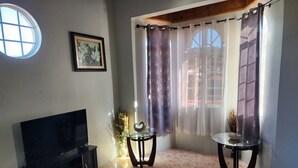 A living room with a TV, two glass tables, a fireplace, and a large window with curtains. - PENTHOUSE VIEW AND FLATS VACATION HOME (#2) (MONTEGO BAY)