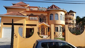 A large, multi-story house with a garage, a balcony, and a circular window design. - PENTHOUSE VIEW AND FLATS VACATION HOME (#2) (MONTEGO BAY)