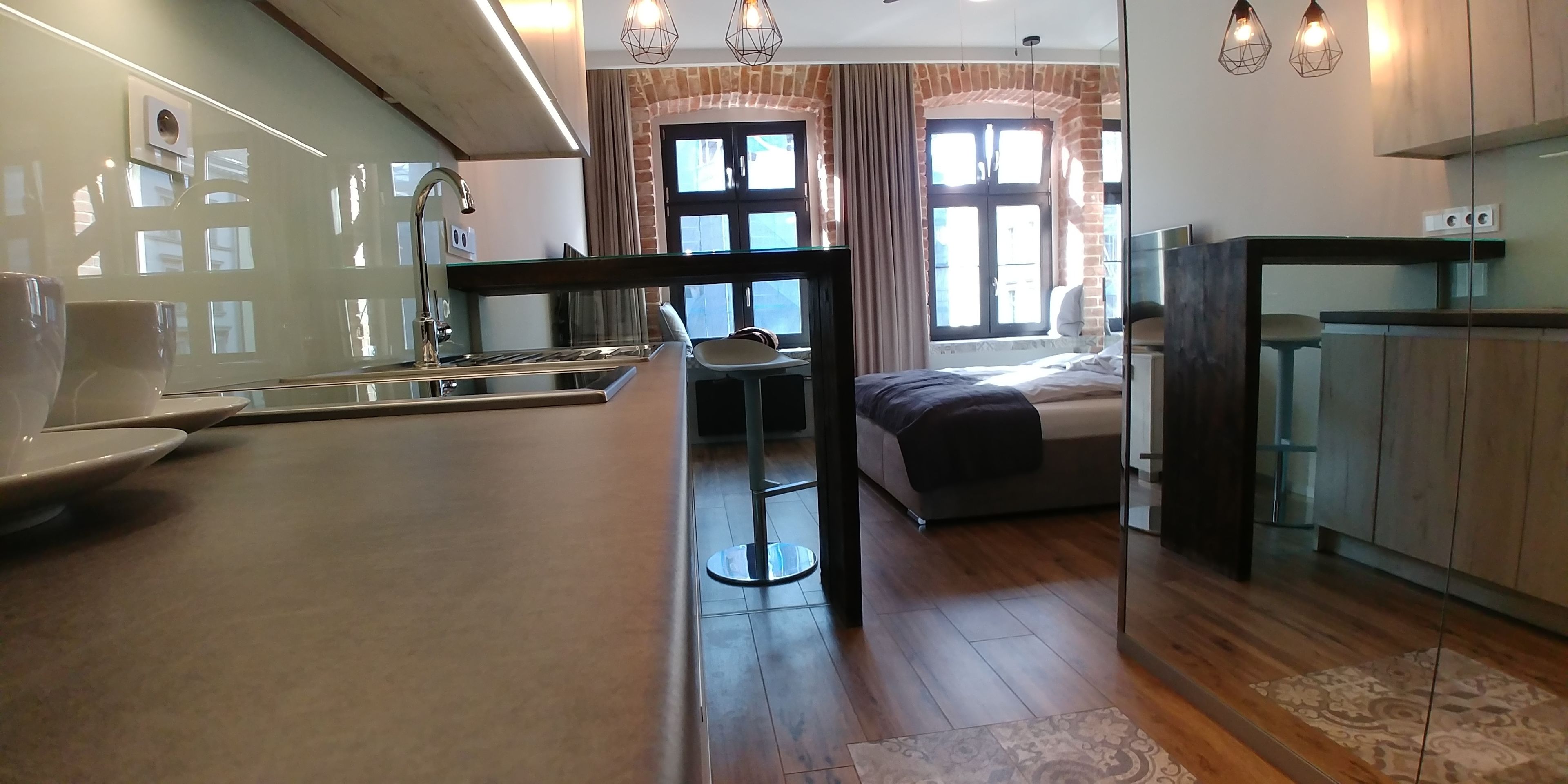 A modern kitchen with a central island, a dining area with a chair, and a bed with a window view.
