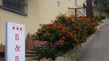 Welcome to B&B La Ganzaria, a charming building with a stone wall and lush gardens.