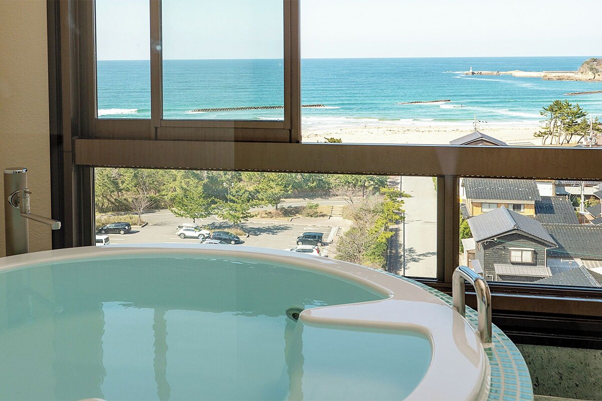 A hot tub with a view of the beach and ocean.