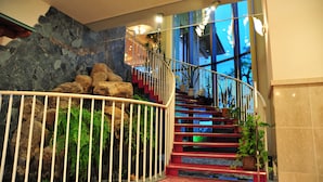 A staircase with a red handrail and a stone wall with greenery. - Kaisyu (Kyotango)