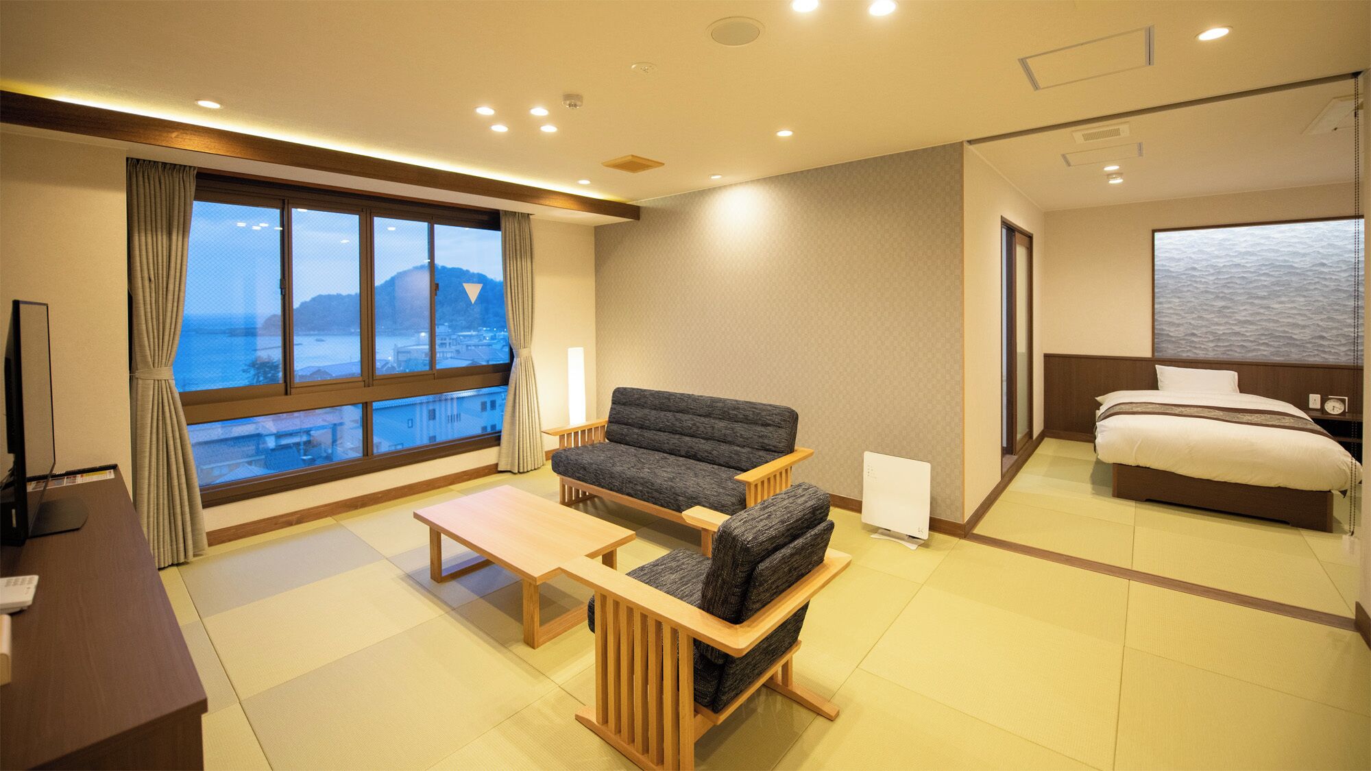Habitación de hotel con sofá, cama, escritorio y vista al mar.