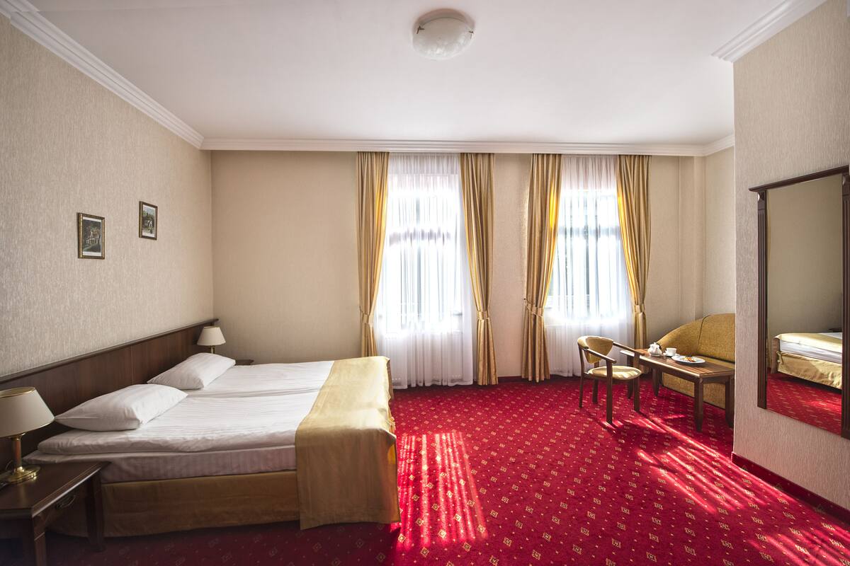 Een hotelkamer met een groot bed, een bureau met een stoel, een kleine tafel en een spiegel.
