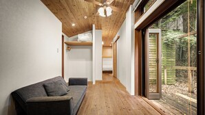 A hallway with a wooden floor, a sofa, and a ceiling fan. - Mountain Home Lodge in Deer Park (Nara)