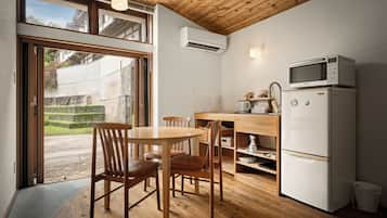 Une cuisine compacte avec un coin repas, un plancher en bois et une vue sur l’extérieur grâce à une porte-fenêtre coulissante.