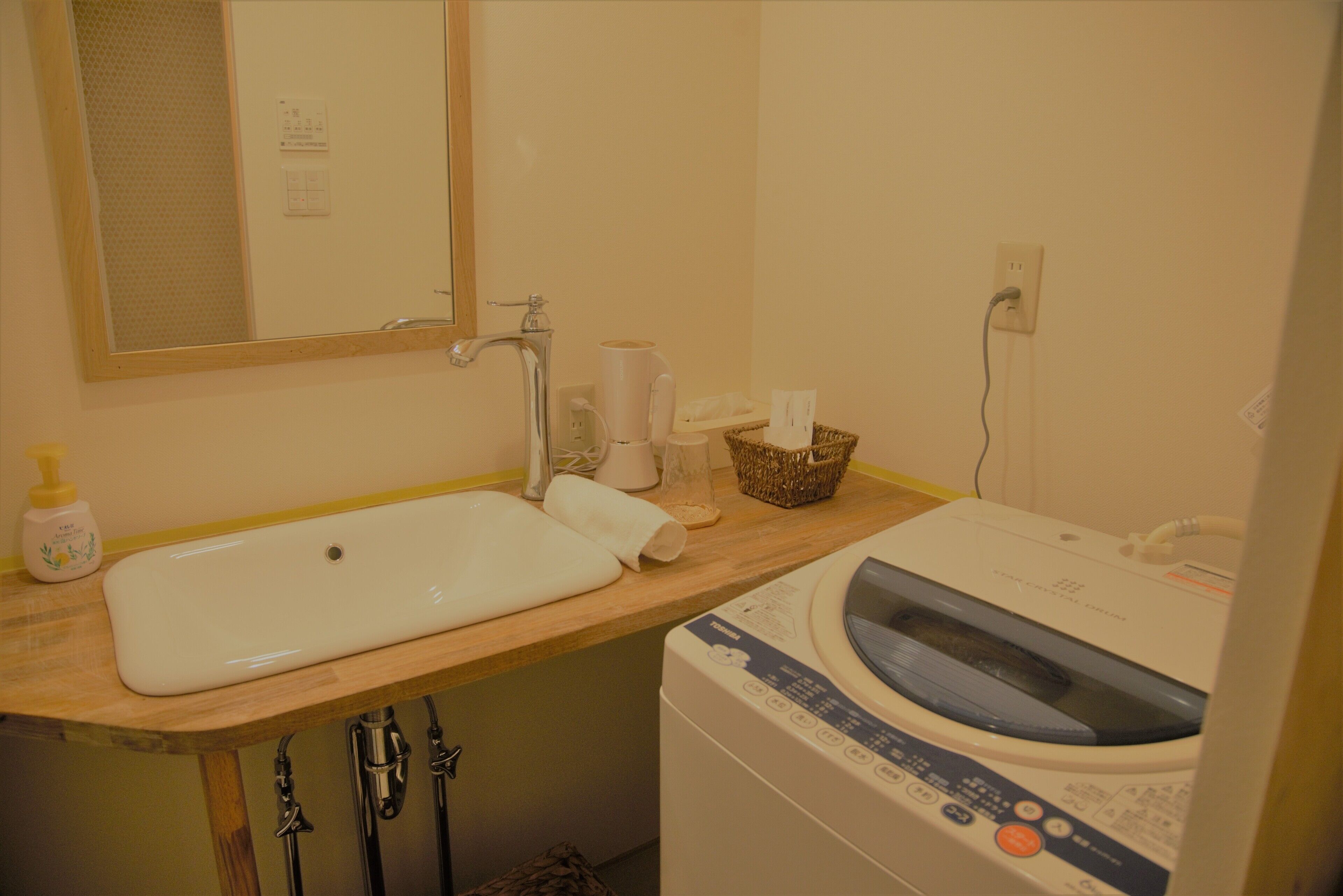 Un baño con lavamanos, espejo y lavadora.