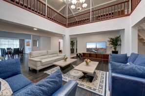 A spacious living area with a high ceiling, a wooden staircase, and a large flat-screen TV. - J5 Four Bedroom Villa in Al Wasl For Family Stay Only (Dubai)