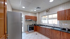 A modern kitchen with wooden cabinets, a stainless steel refrigerator, an oven, and a window providing natural light. - J5 Four Bedroom Villa in Mirdif (Dubai)