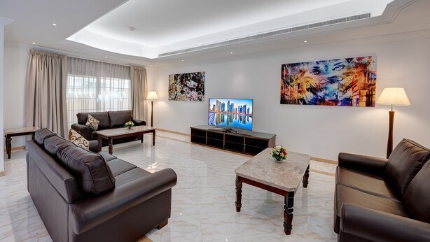 A modern living room with a sofa set, a coffee table, a TV, and artwork on the walls. - J5 Four Bedroom Villa in Mirdif (Dubai)