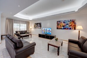 Uma sala de estar moderna com sofá, mesa de centro, televisão e obras de arte nas paredes.