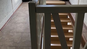 Un escalier avec une rampe blanche menant à un palier.